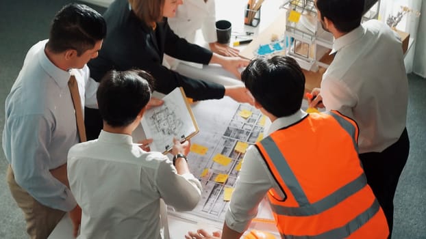 Top view of skilled architect engineer team inspect house model while project manager hold blueprint and asking about building construction. Group of diverse engineer working together. Alimentation.