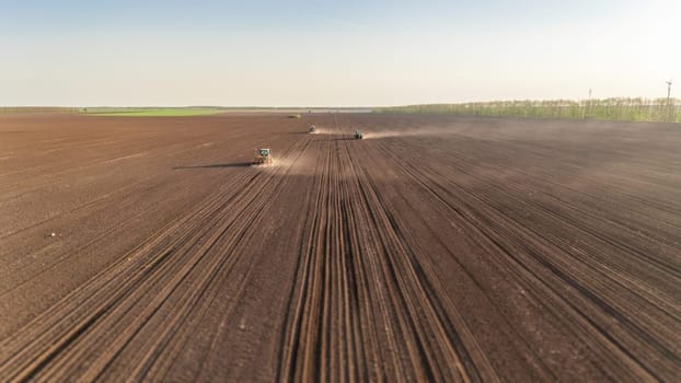 Few Tractors with seed drills sowing the crop, cultivate endless fields and using GPS antennas for straight parallel lines