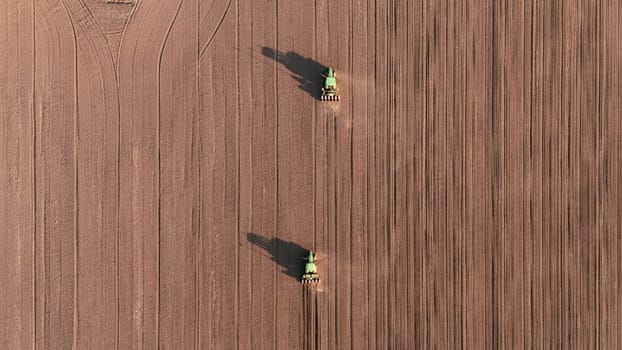 Seeds to sow. Few Tractors with seed drills sowing the crop, top down view from drone