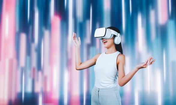 Female standing and wearing white VR headset and white sleeveless connect metaverse, future technology creating cyberspace community. She enjoy looking fantasy light around her. Hallucination.