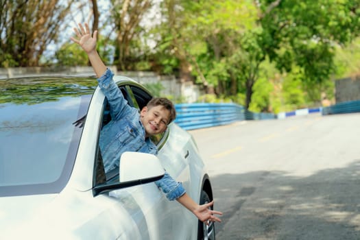 Excited and happy young little boy with smile on his face show up on car window while driving, playful and cheerful expression while on the road trip traveling by car during summertime. Perpetual