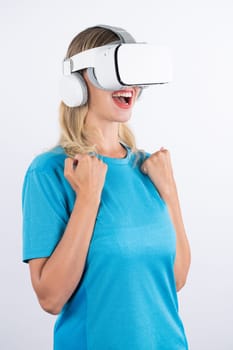 Caucasian happy girl wearing VR glasses and making winner gesture. Skilled woman celebrate while winning game by using VR headsets and standing at pink background. Technology innovation. Contraption.