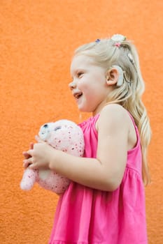 Child girl walks and have fun outdoor with cochlear implant on the head. Hearing aid and treatment concept. Copy space vertical.