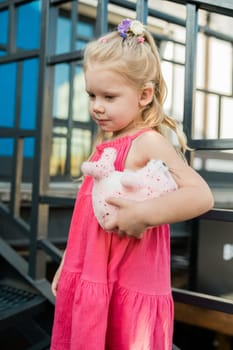 Child girl walks and have fun outdoor with cochlear implant on the head. Hearing aid and treatment concept. Copy space vertical.