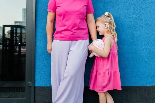 Child girl with cochlear implant with her mother spend time outdoor. Hear impairment and deaf community concept. Deaf and health concept. Diversity and inclusion. Copy space.