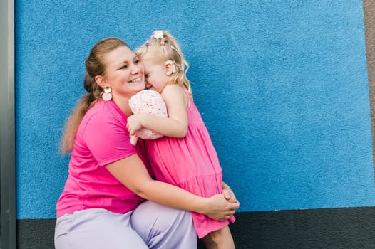 Blonde little girl with cochlear implant playing with her mother outdoor. Hear impairment deaf and health concept. Diversity and inclusion. Copy space.