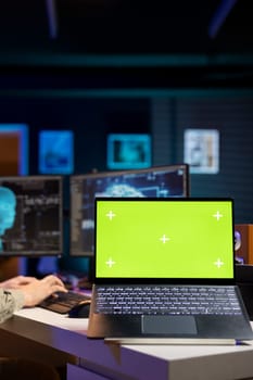 Focus on green screen laptop used by developer to update artificial intelligence machine learning algorithm. Close up of IT expert in apartment using programming to upgrade AI on mockup notebook