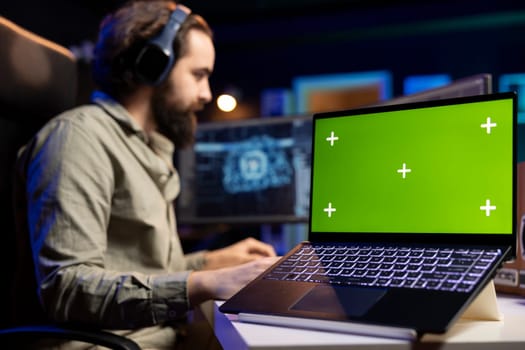 Focus on isolated screen laptop used by engineer updating artificial intelligence machine learning algorithm. Close up shot of chroma key notebook used by IT expert in blurry background programming AI