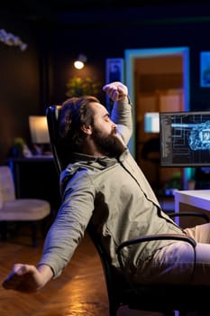 Software technician stretching after using computer all day to build artificial intelligence simulating human brain. Fatigued IT admin relaxing after finishing working with AI neural networks on PC