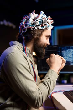 Smiling man with EEG headset on happy after transferring mind into virtual world, becoming one with AI. Cheerful transhumanist celebrating after gaining superintelligence using neuroscientific tech