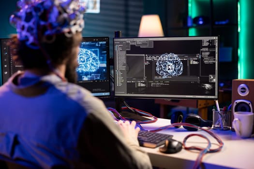 Software technician using EEG headset gear translating thoughts into PC commands using brainwave signals. IT specialist controlling computer functions using mind, helped by scifi technology