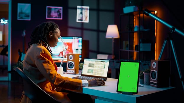 African american business student looking at isolated greenscreen, examining academic software spreadsheet to learn about tax services. Girl using tablet with blank copyspace layout. Camera B.