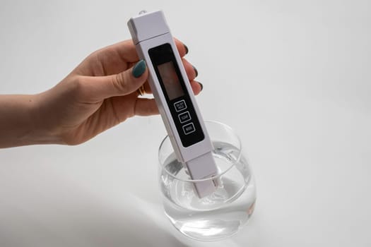 Woman uses a digital conductivity meter to check the purity of water.