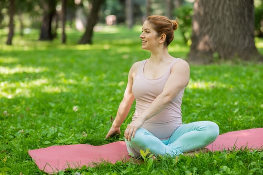 Prenatal yoga. Caucasian pregnant woman doing butterfly pose in the park