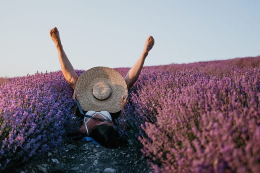 Selective focus. The girls legs stick out of the bushes, warm sunset light. Bushes of lavender purple in blossom, aromatic flowers at lavender fields.