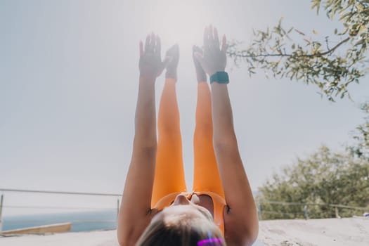 Fitness woman sea. Outdoor workout on yoga mat in park near to ocean beach. Female fitness pilates yoga routine concept. Healthy lifestyle. Happy fit woman exercising with rubber band in park.