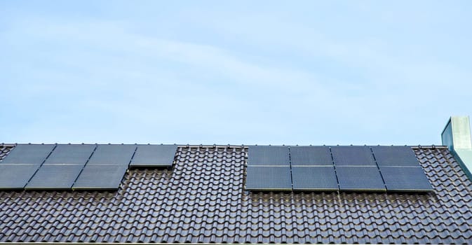 Newly built houses with black solar panels on the roof against a sunny sky Close up of new house with black solar panels. Zonnepanelen, Zonne energie, Translation: Solar panel, Sun Energy