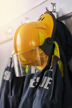Uniform, helmet and jacket of firefighter on wall for rescue, emergency service and protection. Fire brigade, safety gear and equipment, outfit and ppe on rack for health department in station.