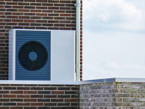 air source heat pump unit installed outdoors at a modern home with bricks in the Netherlands at spring, warmte pomp translation air source heat pump , energy transition from natural gas to electricity
