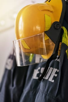 Uniform, helmet and clothes of firefighter on wall for rescue, emergency service and protection. Fire brigade, safety gear and equipment, outfit and ppe on rack for health department in station.
