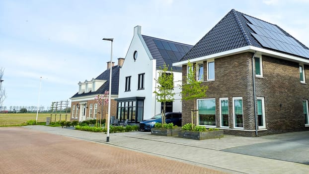 a row of Newly built houses with black solar panels on the roof against a sunny sky Close up of new building with black solar panels. Zonnepanelen, Zonne energie, Translation: Solar panel, Sun Energy