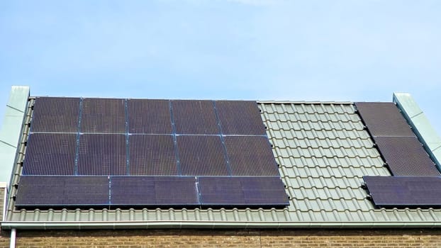 Newly built houses with black solar panels on the roof against a sunny sky Close up of modern family houses with black solar panels. Zonnepanelen, Zonne energie, Translation: Solar panel, Sun Energy