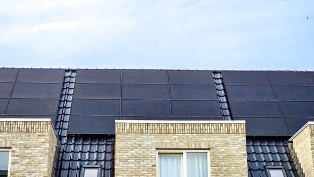 Newly built houses with black solar panels on the roof in Spring, Close up of new building with black solar panels. Zonnepanelen, Zonne energie, Translation: Solar panel, Sun Energy