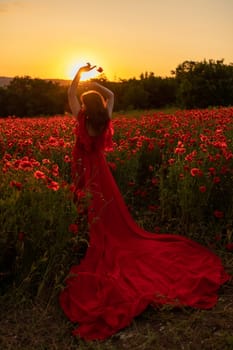 Woman poppy field red dress sunset. Happy woman in a long red dress in a beautiful large poppy field. Blond stands with her back posing on a large field of red poppies.