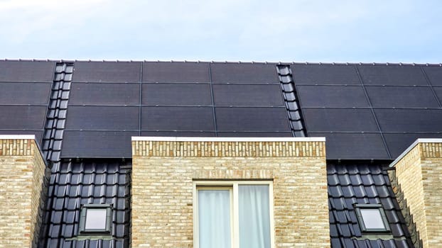 Newly built houses with black solar panels on the roof against a sunny sky Close up of new building with black solar panels. Zonnepanelen, Zonne energie, Translation: Solar panel, Sun Energy