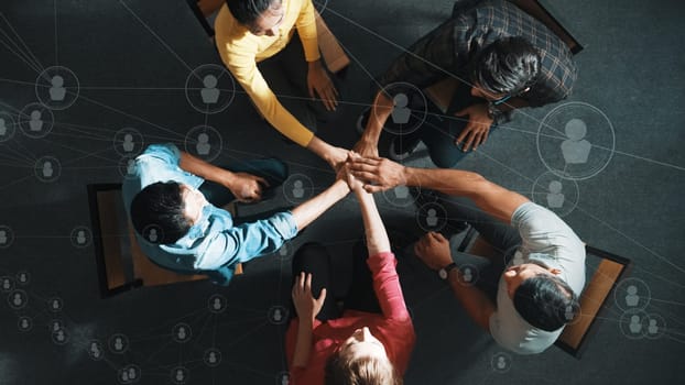 Top aerial view of business people putting hands together to celebrate successful project while sitting chair circle with global networking communication holographic and global connection. Symposium.