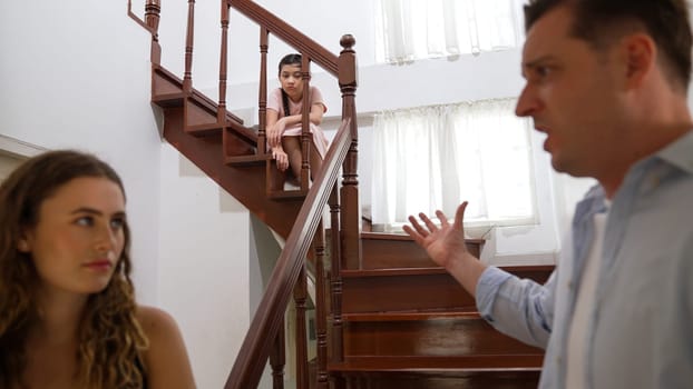 Stressed and unhappy young girl watch her parent arguing from the stair. Domestic violence at home and traumatic childhood develop to depression and anxiety. Unhealthy family concept. Synchronos