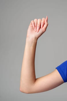 Female hand sign against gray background in studio close up