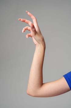 Female hand sign against gray background in studio close up