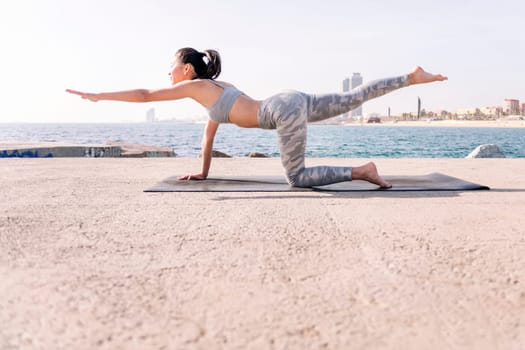 young asian woman in sportswear practicing yoga by the sea, relaxation and healthy lifestyle concept