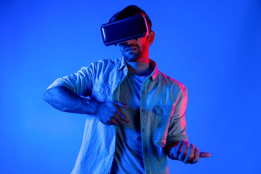 Caucasian smart man wearing VR glass and moving gesture holding gun. Gamer using future digital virtual reality headset or futuristic innovation to enter meta world or playing action game. Deviation.