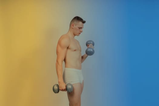 Man with pumped-up body with dumbbells in his hands white panties exercise