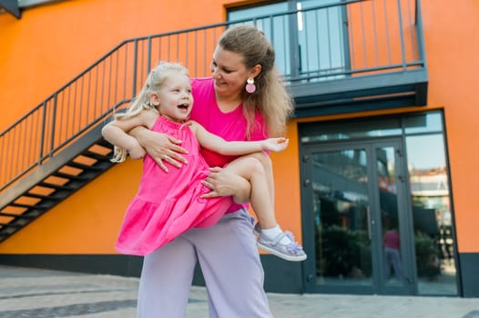 Deaf child with cochlear implant for hearing audio and aid for impairment having fun and laughs with mother outdoor in summer. Sound fitting device to help with communication listening and interaction.