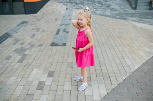 Child walks with cochlear implant hearing aid in summer street. Inclusion and modern technologies for treating hearing loss.