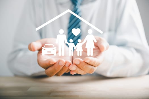 Elevating family concept, Businessman protective gesture resonates with young family silhouette. Health and house insurance icons accentuate safety, reinforcing support and care. Family life insurance