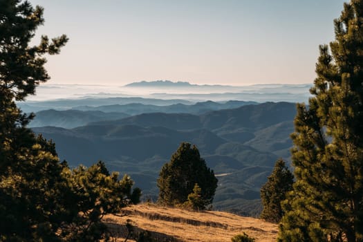 The soft light of sunrise spills over misty mountain ranges, creating a serene view.