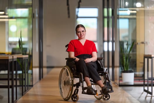 A modern young businesswoman in a wheelchair is surrounded by an inclusive workspace with glass-walled offices, embodying determination and innovation in the business world.