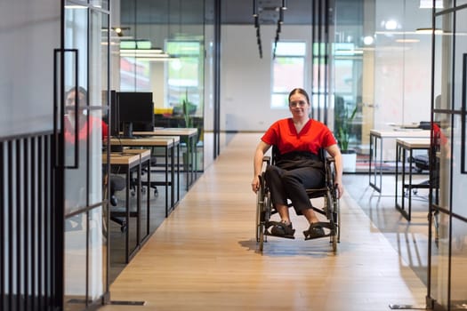 A modern young businesswoman in a wheelchair is surrounded by an inclusive workspace with glass-walled offices, embodying determination and innovation in the business world.