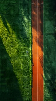 An aerial view of a tennis court nestled among a lush forest of trees, creating a beautiful natural landscape with a harmonious pattern of grass and foliage