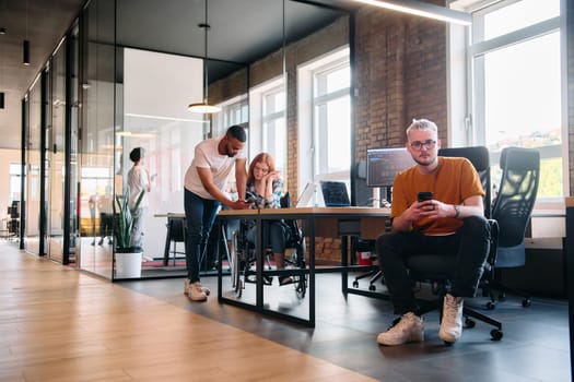 A diverse group of business professionals collaborates in a modern startup coworking center, utilizing a mix of paper-based and technological tools such as mobile phones and computers .