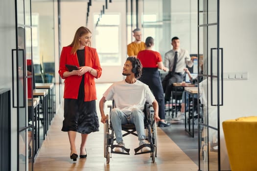 A business leader with her colleague, an African-American businessman who is a disabled person, pass by their colleagues who work in modern offices.