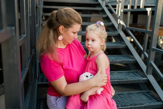 Child girl with cochlear implant with her mother spend time outdoor. Hear impairment and deaf community concept. Deaf and health concept. Diversity and inclusion. Copy space.