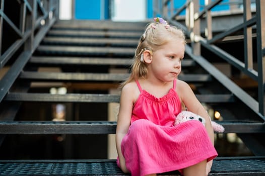 Child walks with cochlear implant hearing aid in summer street. Inclusion and modern technologies for treating hearing loss.