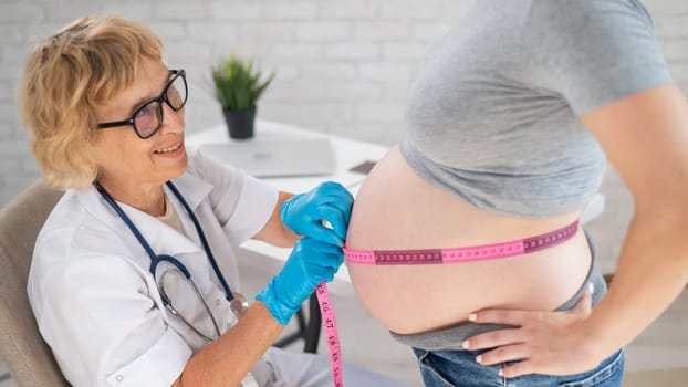 Doctor measuring the volume of a pregnant woman's abdomen using a centimeter tape