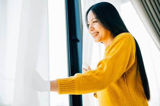 A young woman opens curtains smiles at the view feeling refreshed and joyful at home. Reflecting morning happiness relaxation and a cheerful beginning.