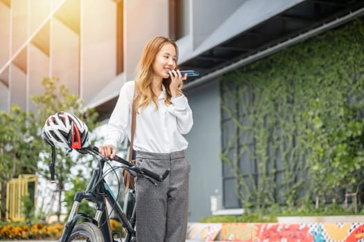 A businesswoman takes a moment to cycle through the city smartphone in hand. Her smile and relaxed posture reflect the balance of work joy and connectivity in the modern world.